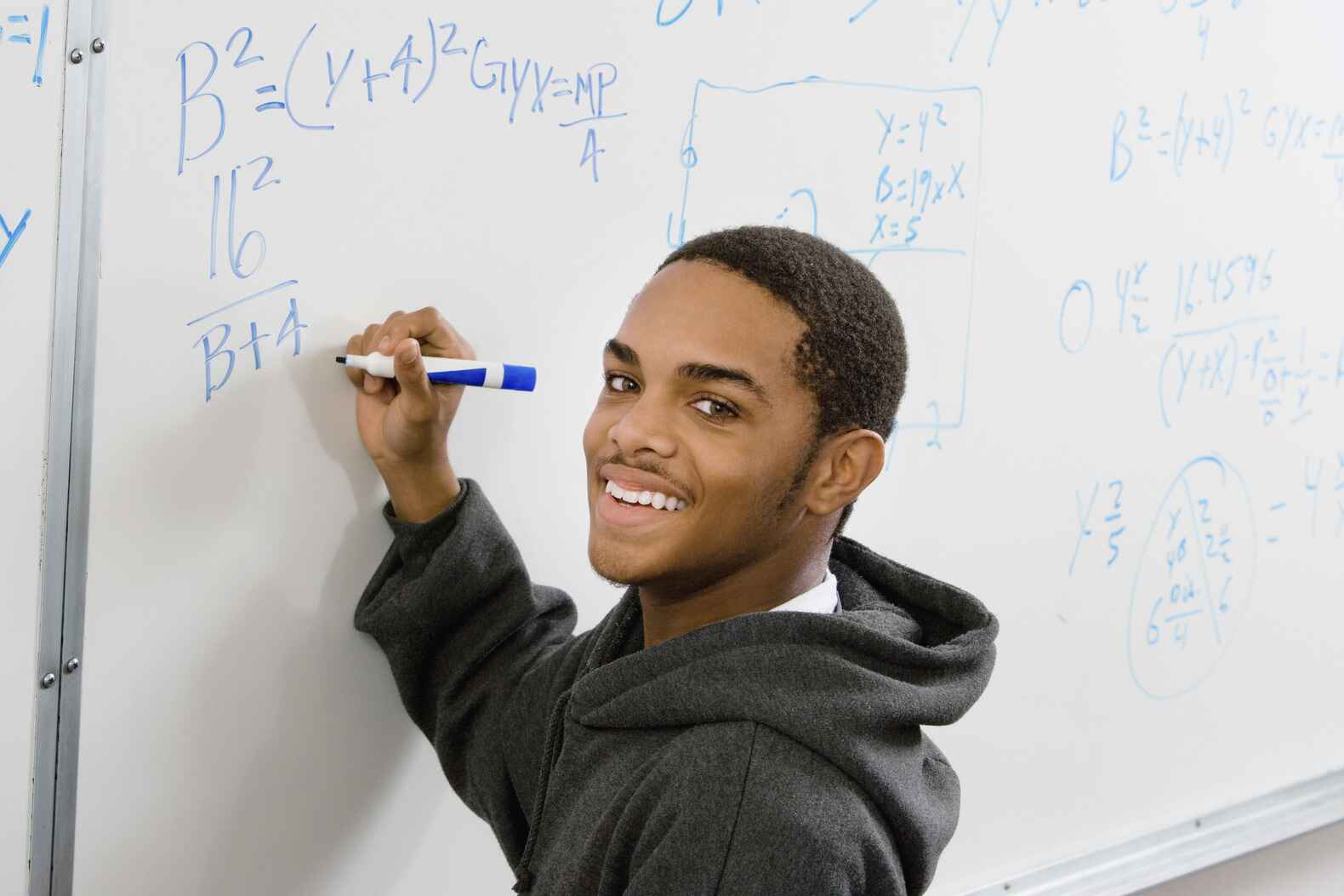 teen boy doing math on a whiteboard