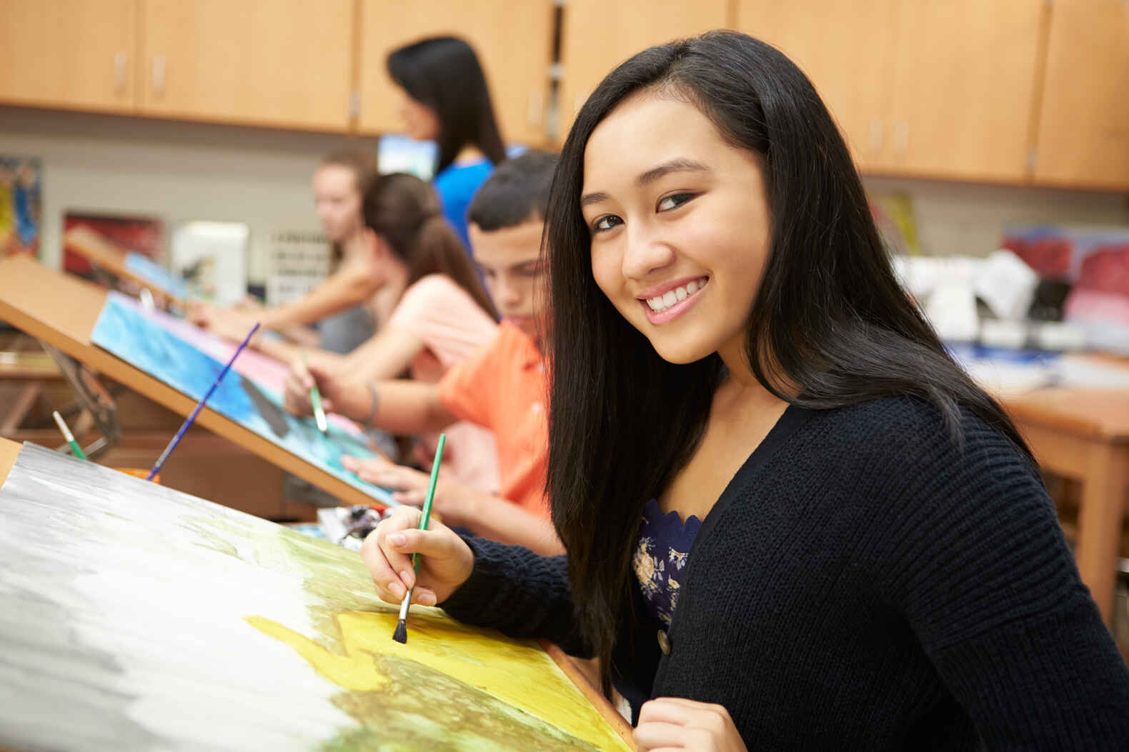 teen girl painting in art class