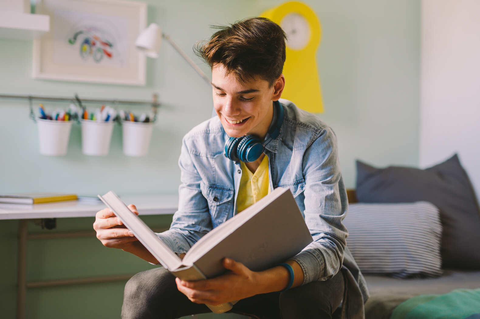 teen boy reading a book in his room